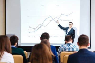 Presenter pointing at a line graph during a business presentation.