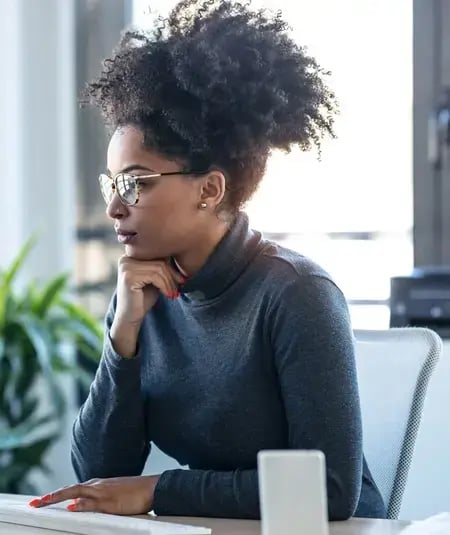 woman in front of computer with hand on chin